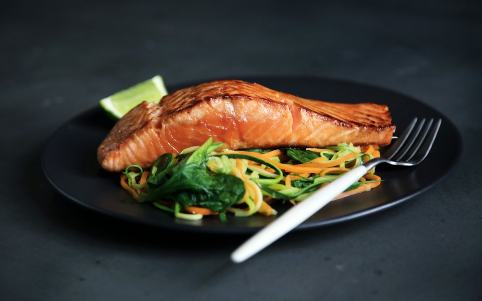 Grilled salmon with vegetables on a dark plate